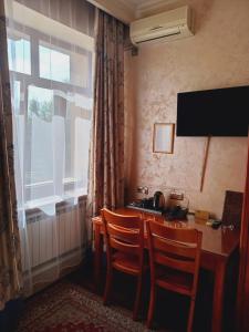 a room with a desk with two chairs and a window at Ak zhol in Almaty