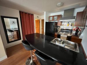 een keuken met een zwart aanrecht en een wastafel bij Harbor Light-Modern 1BR King-Complete Unit in Vancouver