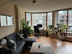 een woonkamer met een bank, een bureau en ramen bij Harbor Light-Modern 1BR King-Complete Unit in Vancouver
