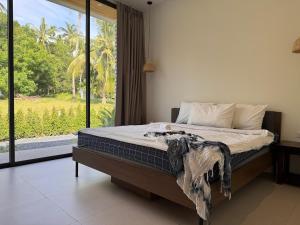 ein Schlafzimmer mit einem Bett und einem großen Fenster in der Unterkunft Modern Pool Villa Escape in Koh Phangan in Ko Phangan