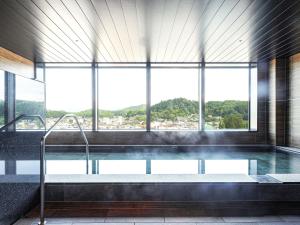a large swimming pool in a building with a large window at HOTEL AMANEK HidaTakayama in Takayama