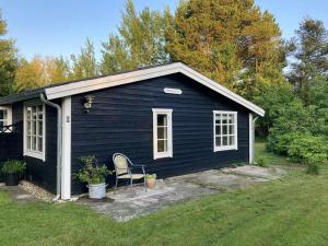 a black house with a chair in front of it at Summerhouse Near Marielyst Beach With Large Garden in Marielyst