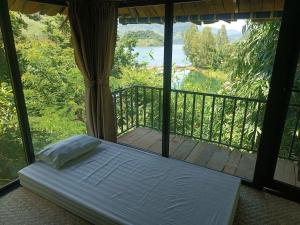 a bed in a room with a view of a balcony at Mường Trai Homestay in Sơn La