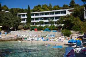 a beach with chairs and people in the water at Hotel Sirena Hvar in Hvar