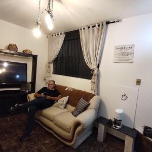 ein Mann, der auf einer Couch in einem Wohnzimmer sitzt in der Unterkunft Apart Madrid Yanahuara in Arequipa