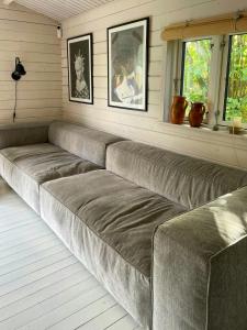 a large couch in a room with two windows at Holiday Home Near Tisvilde Forest And Rhubarb Farm in Vejby Strand