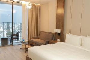 a hotel room with a bed and a chair at The Tropical Oceanview Nha Trang in Nha Trang