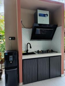 a kitchen with a sink and a stove and a microwave at ZZD Gunong Roomstay in Bachok +17 photos
