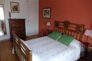 Un dormitorio con una gran cama de madera con almohadas verdes en Casa Rural del Sol, en Zamarramala