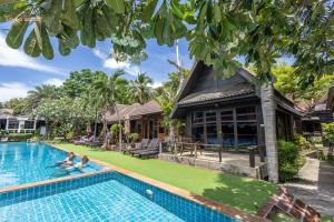a villa with a swimming pool in front of a house at Tommy Resort in Haad Rin