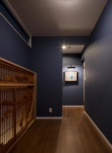 a hallway with blue walls and a wooden staircase at yah homes takasago in Fukuoka
