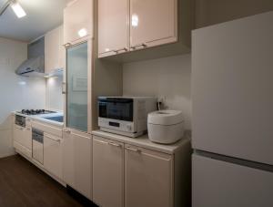 a kitchen with white cabinets and a microwave at yah homes takasago in Fukuoka