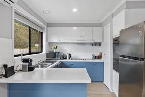 a kitchen with white and blue cabinets and a refrigerator at The Pawfect Beach House in Cowes
