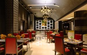 a restaurant with tables and chairs and a chandelier at Udman Hotel Chhattarpur in New Delhi