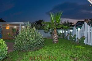 a white fence with a palm tree in a yard at Red House Family Hotel in Ravda