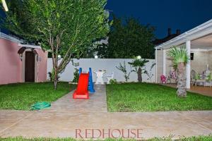 a yard with a playground with a red slide at Red House Family Hotel in Ravda +69 photos