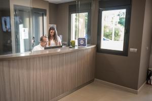 Un hombre y una mujer sentados en un mostrador de recepción. en Hotel Miguel Sanchez, en Alhaurín de la Torre