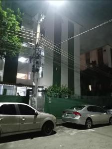 Dos coches estacionados en un estacionamiento frente a un edificio. en Rodrigues Hostel, en Río de Janeiro