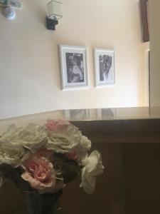a vase of flowers sitting on a counter with three pictures at Red House Family Hotel in Ravda
