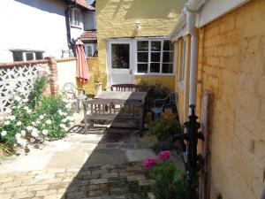 a patio with a wooden table and benches on a house at Minsmere Cottage in Yoxford