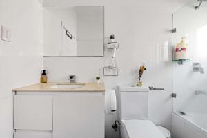 a white bathroom with a toilet and a sink at Freshly Modernized Single Room- Well-Connected Suburb Shared Bathroom in Epping
