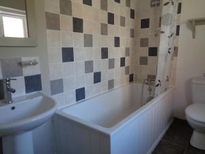 a bathroom with a tub and a sink and a toilet at Minsmere Cottage in Yoxford