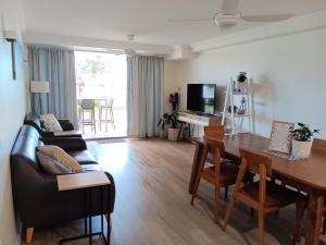 a living room with a couch and a dining room table at Oceanfront Ground Floor Apartment - Dwell 3 in Bargara in Bargara