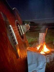Una guitarra está junto a un fuego. en Espaço fazendinha por do Sol da piscina, en Paty do Alferes
