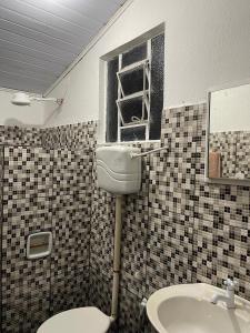 Un baño con inodoro, lavabo y ventana. en Espaço fazendinha por do Sol da piscina, en Paty do Alferes