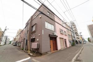 een roze gebouw aan de kant van een straat bij Nakajima Park West House / Vacation STAY 5418 in Sapporo