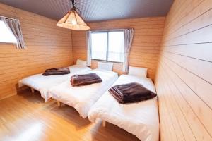drie bedden in een kamer met houten wanden bij Nakajima Park West House / Vacation STAY 5418 in Sapporo