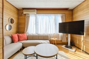een woonkamer met een bank en een flatscreen-tv bij Nakajima Park West House / Vacation STAY 5418 in Sapporo