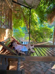 a little girl laying on a bench on a porch at Secret Garden hostel in Nguyên Ngoại