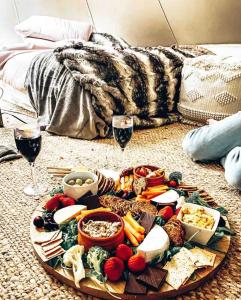 a plate of food and two glasses of wine at Aura Glamping Bell Tent in Eumundi