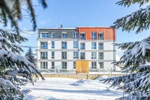 un edificio blanco con techo rojo en la nieve en Heřmánek by Mountain ways, en Abertamy
