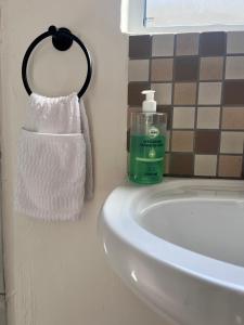 a bathroom sink with a bottle of soap and a towel at Relaxa Sleep & Go - Self Catering Accommodation in Cape Town +6 photos