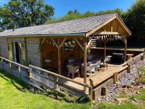 a wooden pavilion with a table and chairs on a deck at The Cabin at Tedburrow rural retreat perfect for couples in Culmstock