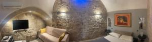 a living room with a couch and a stone wall at Dimora Mazzini in Trani