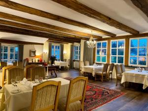 a restaurant with tables and chairs and windows at Romantik Waldhotel Mangold in Bergisch Gladbach