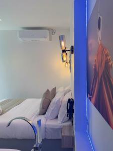 a bedroom with a bed with white sheets and a painting at La Costa Hotel 15 Min from Airport,Free High-Speed WiFi, Spa Bath, Pool & Restaurant in Katunayaka