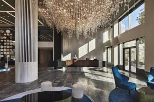 a lobby with a chandelier and chairs and tables at Grand Hyatt Athens in Athens