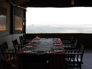 a long table in a room with chairs and a large window at African Sunrise Lodge and Campsite in Mto wa Mbu