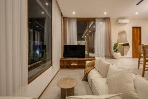 Una sala de estar con un sofá blanco y un televisor. en New cozy 2-Bedroom Ocean View Villa, en Uluwatu