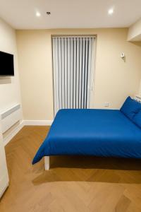 Cette chambre dispose d'un grand lit bleu et d'une fenêtre. dans l'établissement 30C The Luxury Studios near Arsenal and Central London, à Londres 2 autres photos