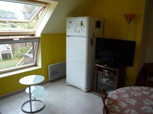 a kitchen with a refrigerator and a table and a tv at Briois Cristelle in Penmarcʼh +12 photos