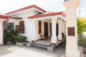 a white house with a chair on the porch at Villa Sea Wave in Hikkaduwa