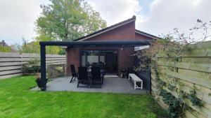 a patio with chairs and a table in a yard at Luxe vakantiebungalow met omheinde tuin voor hond en kinderen in Dirkshorn