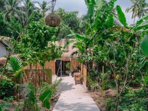 a path in a garden with trees and a house at Brezze Garden Village in Mataram