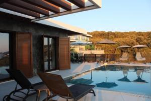 a pool with chairs and umbrellas next to a building at Luxury Villa Lorcrimar in Masline