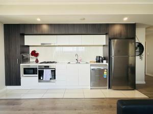 MerrylandsにあるMerrylands 2bedrooms Apt with free car parkingの白いキャビネットとステンレス製の冷蔵庫を備えたキッチン +11枚の写真